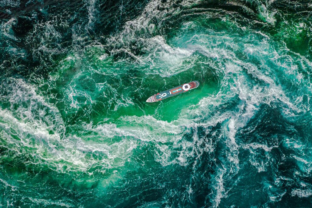 A lone boat struggling amidst treacherous sea waters, symbolizing the perilous journey of battling alcoholism, a progressive disease.